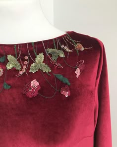 the back of a red dress with flowers on it's chest and neckline