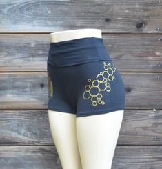 Honeybee Hot ShortsThese comfortable and stylish black  high waisted hot shorts feature a metallic gold honeybee design. The outside of the right leg is decorated with a screen print of my hand drawn sacred geometric honeybee image. They are finished off with a gold honeycomb on the outside of the left leg.All images were hand drawn and screened.Made in the USA95% Cotton / 5% SpandexAvailable in sizes:SMALL, MEDIUM, LARGE and X-LARGEPlease check out my Instagram @UriahClearLight to learn more ab Gold Fitted Bottoms Short Length, Fitted Gold Bottoms Short Length, Gold Fitted Short Bottoms, Gold Stretch Bottoms Short Length, Gold Stretch Short Bottoms, Fitted Gold Shorts For Summer, Fitted Gold Shorts, Honeybee Design, Sacred Geometric