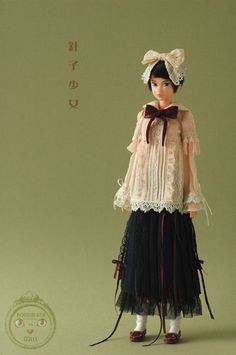 the doll is wearing a dress and hat with laces on it's head