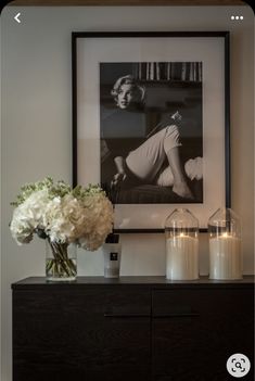 a black and white photo on the wall above a dresser with candles in front of it