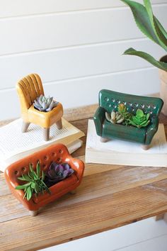 three ceramic planters sitting on top of a wooden table next to an open book