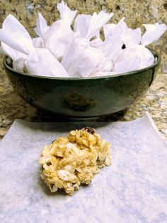 a bowl filled with white tissue paper next to a cookie on top of a counter