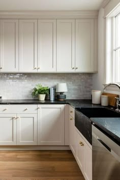 a kitchen with white cabinets and black counter tops