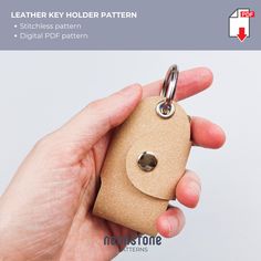 a hand holding a leather key holder in it's left hand with the tag attached