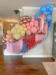 balloons and streamers are arranged in the shape of an i - letter on a wall