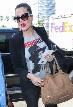 a woman carrying a brown purse and wearing sunglasses