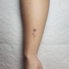 a small flower tattoo on the left calfocks is shown in this image, it looks like a dandelion