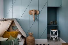 a room with a teepee tent and pillows on the floor, next to a shelf