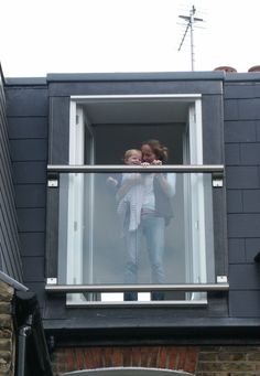 two people standing on a balcony looking out the window