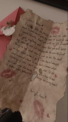 a piece of paper with writing on it next to a pink envelope and white flower