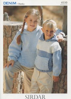 two children in sweaters and pants standing next to each other with their arms around the shoulders