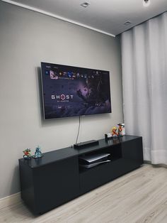 a flat screen tv sitting on top of a black entertainment center next to a window