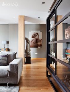 a living room filled with furniture next to a wall mounted book shelf and a painting on the wall