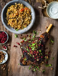 a large piece of meat on a cutting board next to bowls of food and condiments