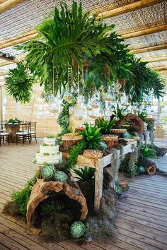 a table topped with lots of green plants next to a wooden floor covered in greenery