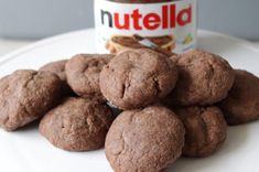 a white plate topped with chocolate cookies next to a jar of nutella