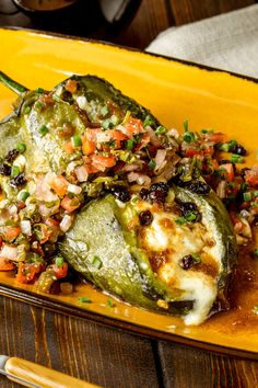 a yellow plate topped with a stuffed green pepper covered in lots of toppings on top of it