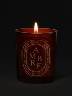 a candle that is lit in the dark with an ambre logo on it's side