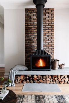 a wood burning stove in a living room next to a pile of firewood on a rug