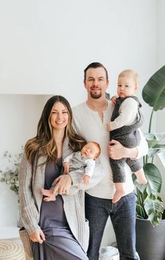 a man, woman and baby are posing for a photo in front of a potted plant