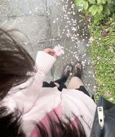 a woman is sitting on the ground with her feet up and holding a flower in her hand