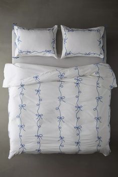 an unmade bed with two pillows and blue string on the comforter, next to a pillow case