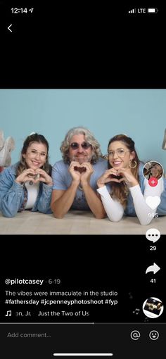 two women and a man are holding their hands in the shape of hearts while sitting on a bed