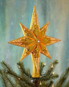 a gold star ornament on top of a christmas tree with green and blue background