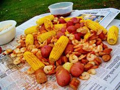 corn on the cob, potatoes and shrimp are sitting on top of newspaper paper