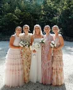 a group of women standing next to each other on a gravel ground with trees in the background