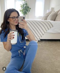 a woman sitting on the floor taking a selfie with her phone and holding a cup