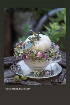 a white bowl filled with flowers and pumpkins