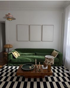 a living room with a green couch and black and white checkered rug