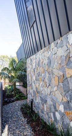 a stone wall next to a wooden fence and palm trees on the side of a building