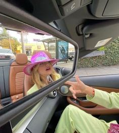 a woman sitting in the passenger seat of a car with a pink hat on her head