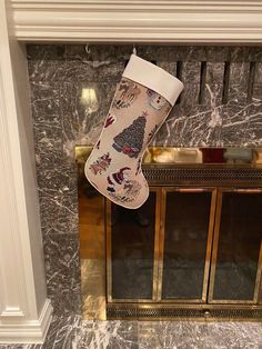 a christmas stocking hanging from the fireplace mantel in a room with marble walls