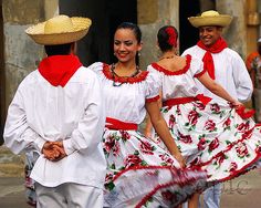 three people in white and red dresses walking down the street