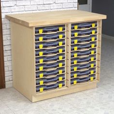 a large wooden cabinet filled with lots of blue and yellow boxes next to a brick wall