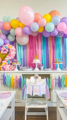 a birthday party with balloons and streamers on the wall, cake table and decorations