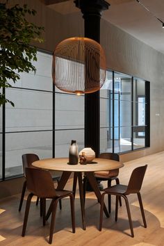 a wooden table with four chairs around it in front of a large window and a plant