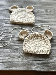 two crocheted hats with ears are sitting on a wooden table next to each other