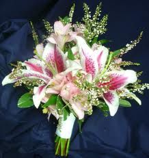 a bouquet of flowers is sitting on a dark blue cloth with white and pink lilies