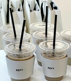 six cups with black straws in them sitting on a table