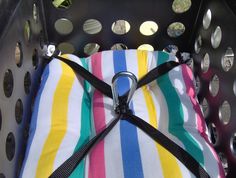 a colorful striped bag sitting on top of a laundry hamper filled with lots of coins