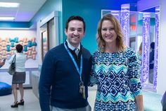 a man and woman standing next to each other in a room with blue lighting on the walls