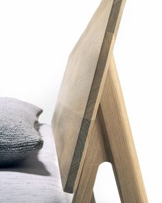 a wooden chair sitting next to a pillow on top of a bed