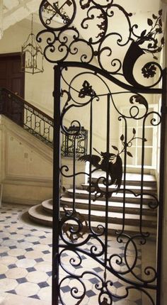 an ornate iron gate in the entrance to a house with tiled flooring and stairs