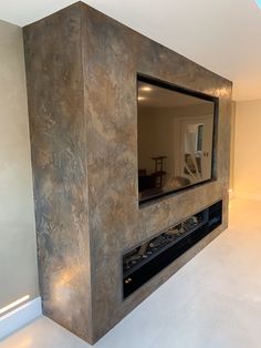 a fireplace with a mirror above it in a room that has white floors and walls