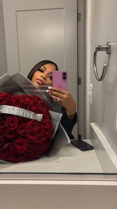 a woman taking a selfie in front of a mirror with a bouquet of roses