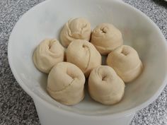 a white bowl filled with doughnuts on top of a table